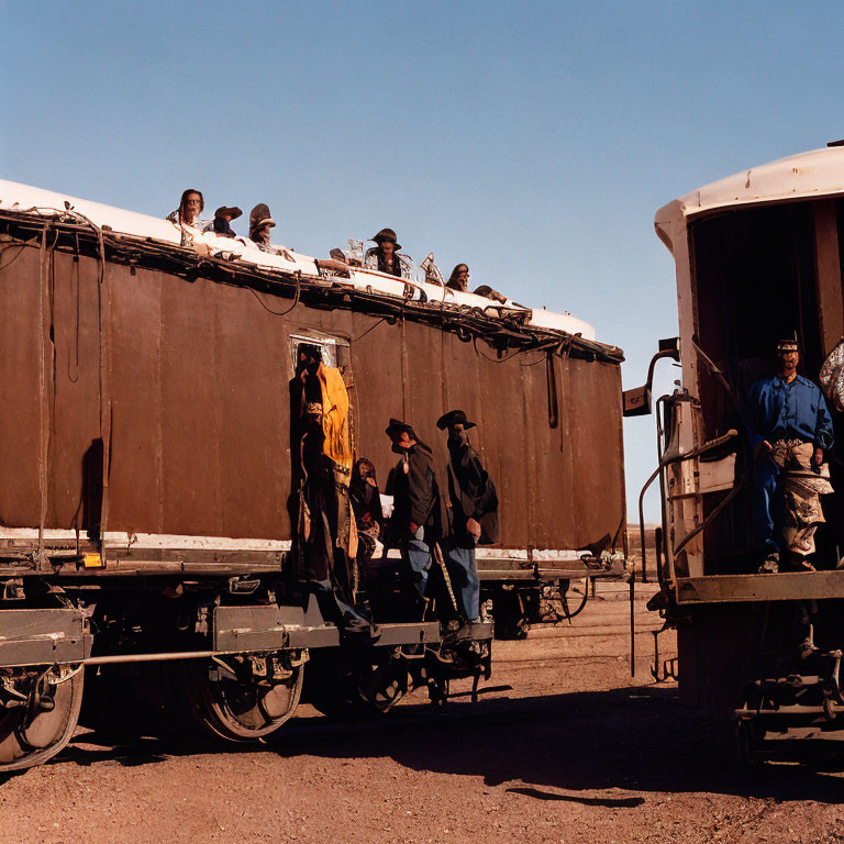 Vintage train passengers seated and standing, person in blue coveralls on platform
