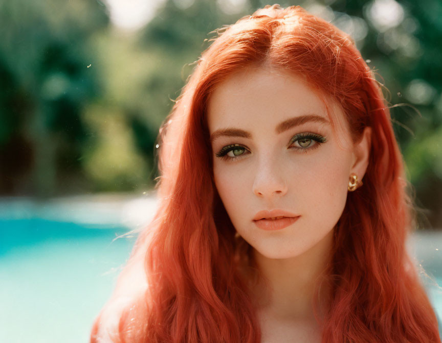Vibrant red hair and green eyes woman by pool in sunlight