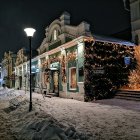 Winter street scene with snowfall and festive decorations.