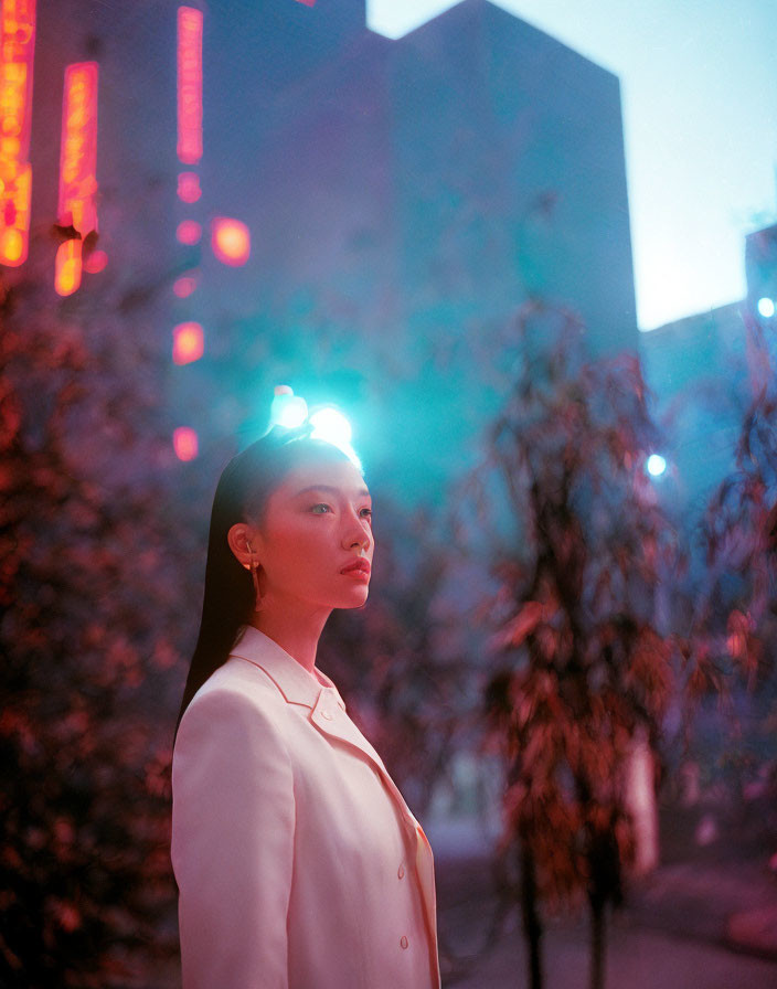 Woman in white blazer standing at dusk with city lights, featuring a small light on her forehead.