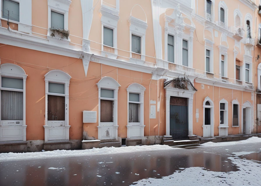 Pastel Orange Building with Arched Windows Reflecting Snow in Puddle