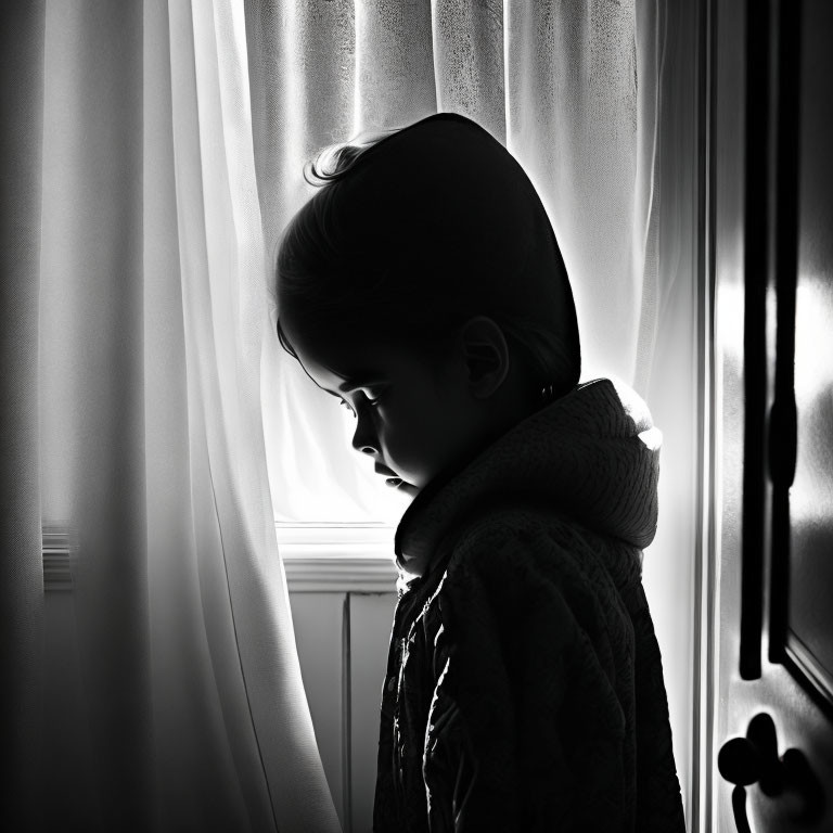 Silhouette of young child in dimly lit room with soft backlight