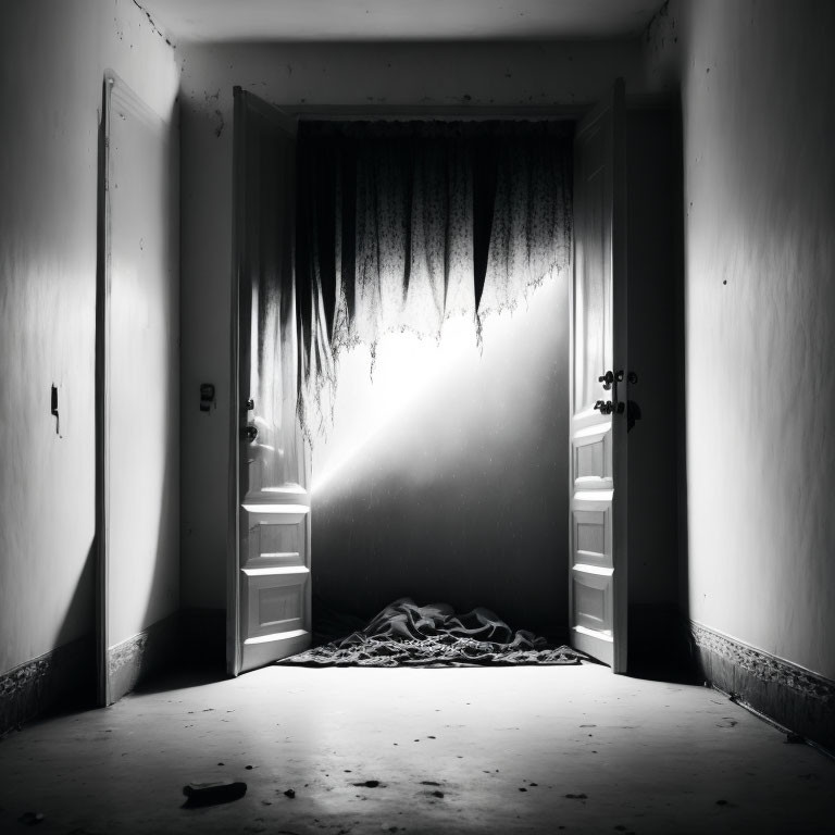 Monochrome photo of dimly lit room with tattered curtain and diagonal shadow