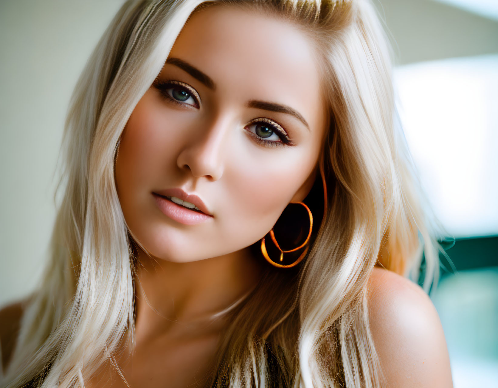 Blonde woman portrait with hoop earrings and subtle makeup