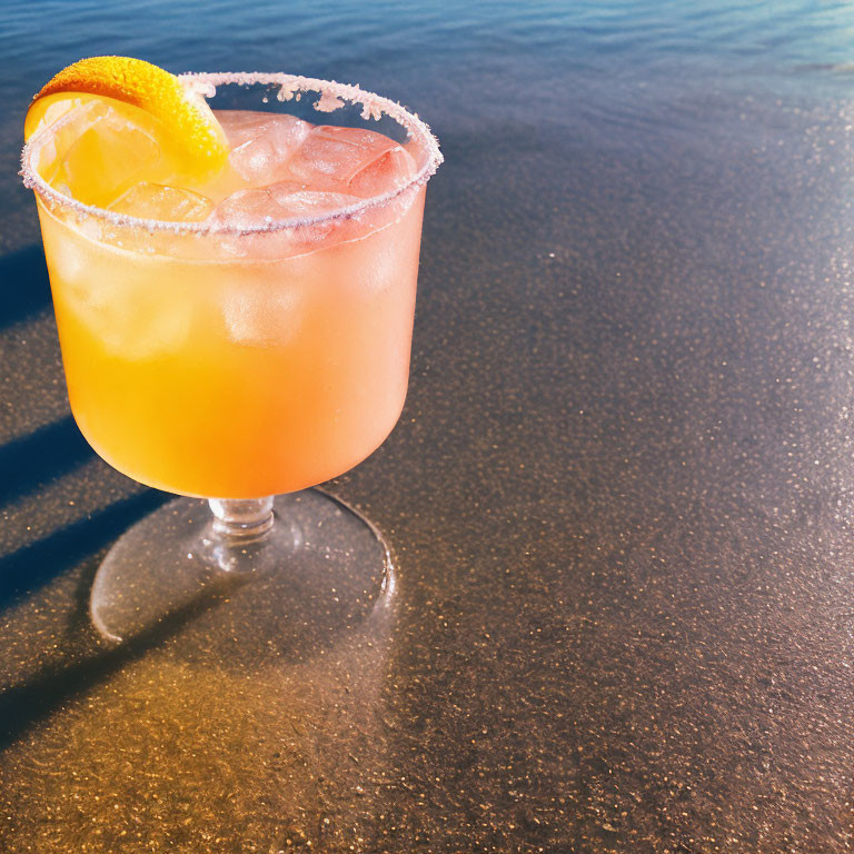 Orange Cocktail with Ice and Lemon Slice on Beach Background