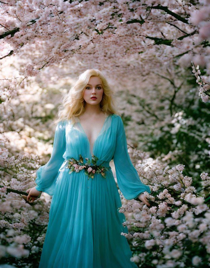 Woman in blue dress surrounded by cherry blossoms and natural light