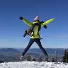 Person in Yellow Jacket Jumping Over Snowy Mountain Landscape with Crescent Moon