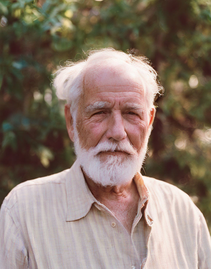 Elderly man with white beard and moustache in light-colored shirt outdoors