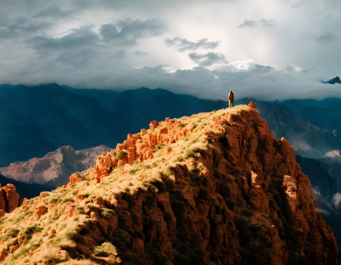 Hiker on rugged cliff with dramatic sky and mountains