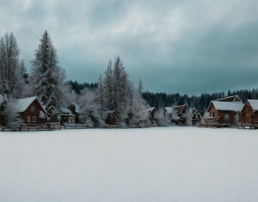 Snow-covered wooden cabins and frosted trees in serene winter setting