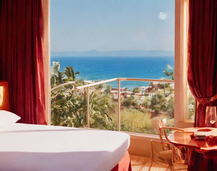 Bright room with sea view balcony, red curtains, white bed, and dining area with greenery.