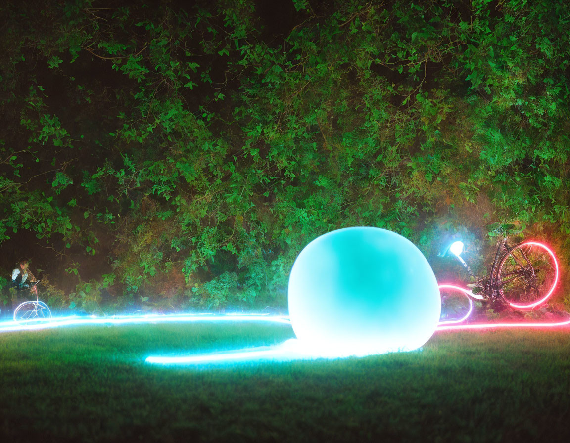 Colorful lights illuminate orb, bicycle, and person in park at night