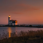 Tranquil sunset scene with lighthouse by calm lake