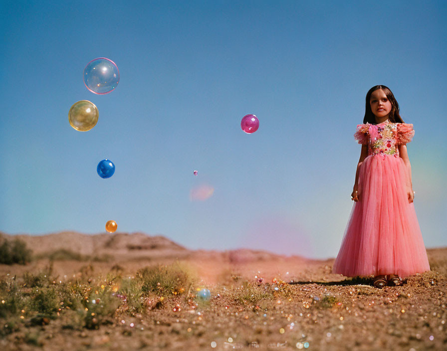 Young girl in pink dress in desert with floating bubbles