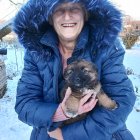 Smiling woman with puppy and dog in snowy street scene