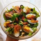 Fresh Spinach Salad with Boiled Eggs, Bacon, Olives, and Broccoli in Glass Bowl
