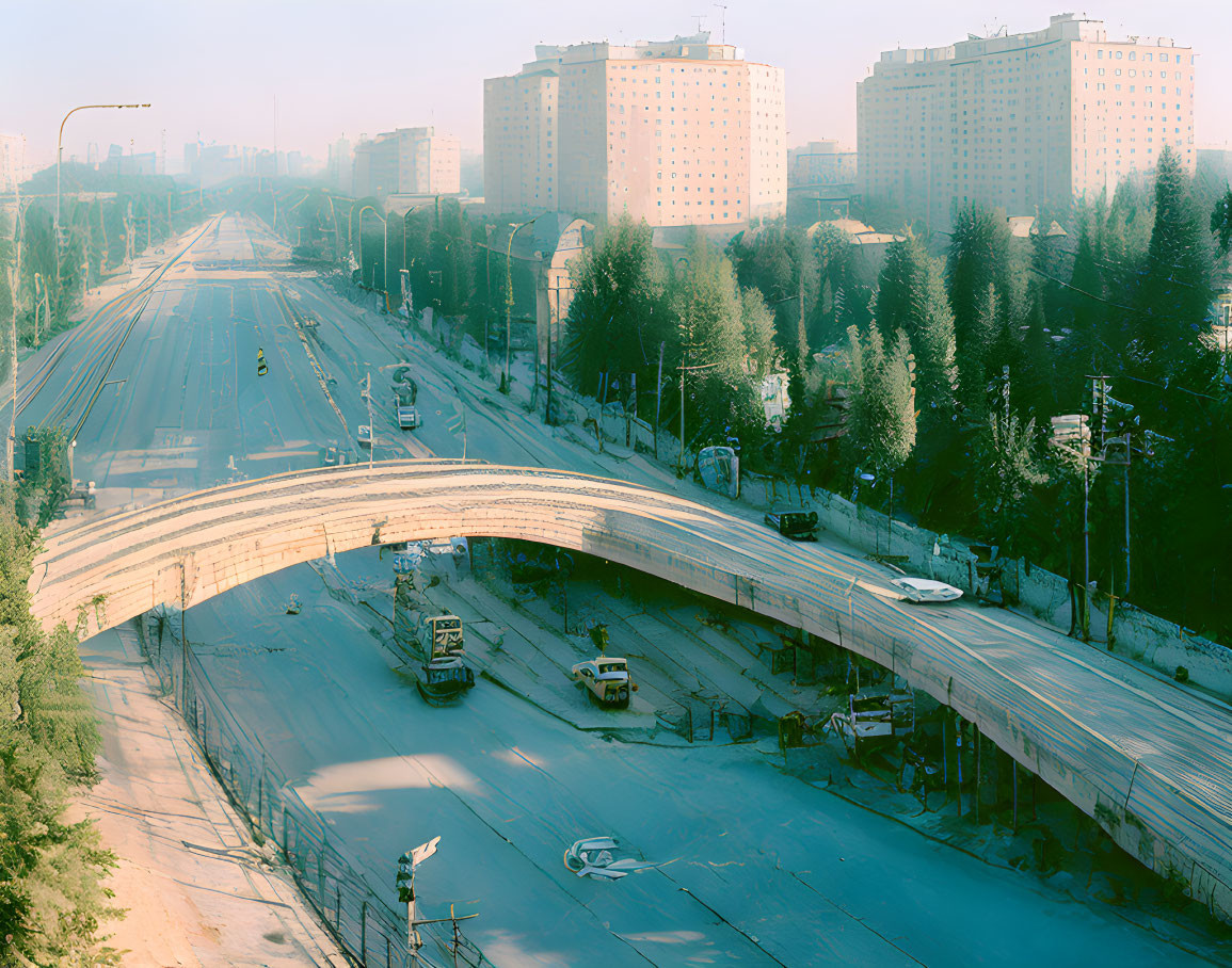 City overpass with light traffic, trees, buildings, and clear sky in warm light