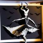Paper art of stylized female figure with bat-like wings and castle silhouette.