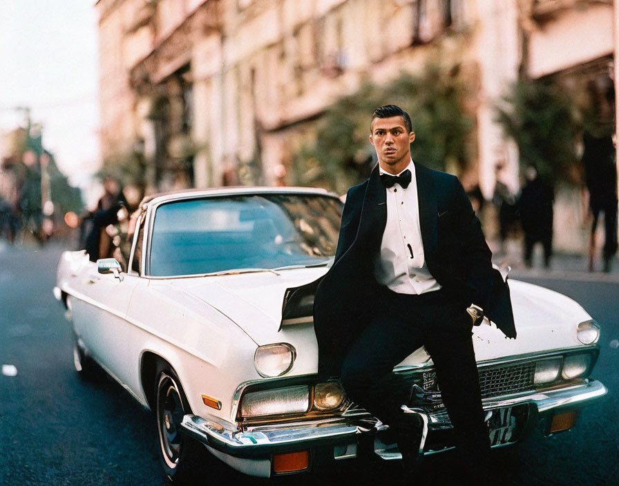 Man in Tuxedo Sitting on Vintage White Car in City Street