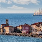 Picturesque Coastal Town with Colorful Buildings, Lighthouse, Arched Bridge, and Sailboats