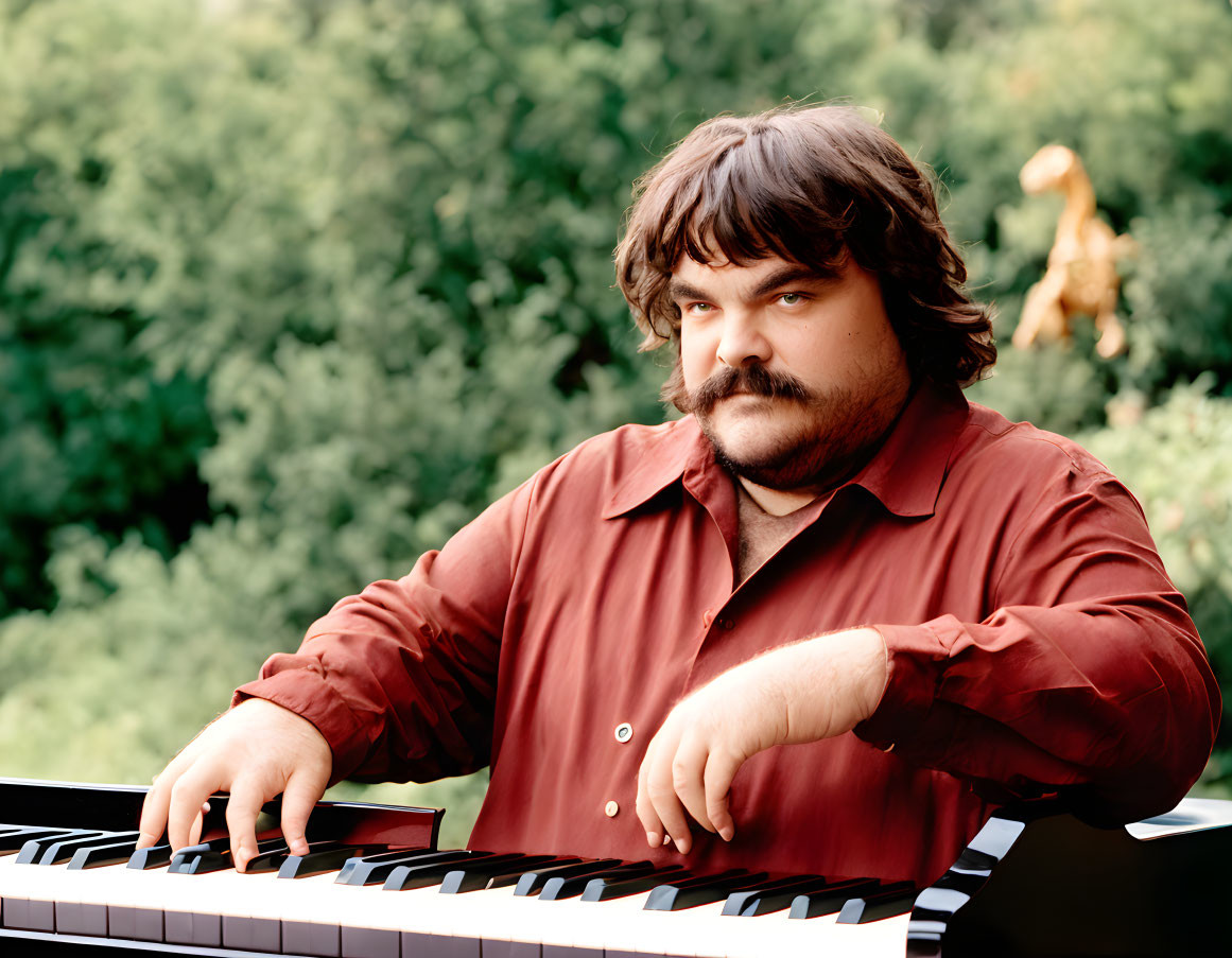 Brown-haired man playing piano outdoors with trees in background