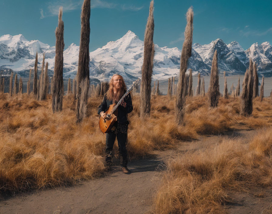 Man with long curly hair playing electric guitar in field with mountains in background