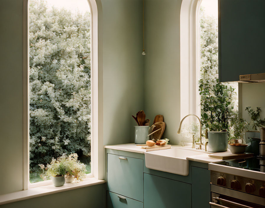 Tranquil kitchen with teal cabinetry, white countertops, hanging utensils, and greenery view