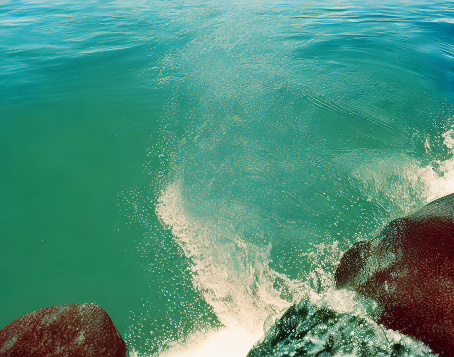 Swirling Turquoise Ocean Water Around Red-Brown Rocks