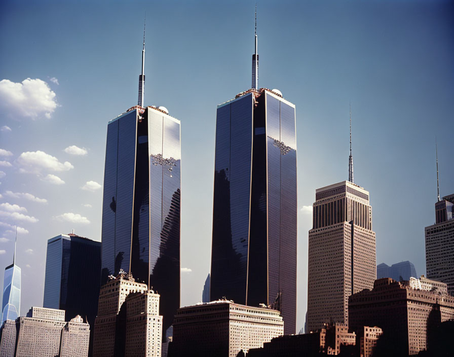 Iconic twin towers and city skyscrapers under blue sky.