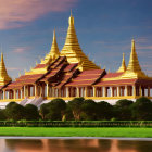Traditional temple with gold spires and red roofs at sunset by the water