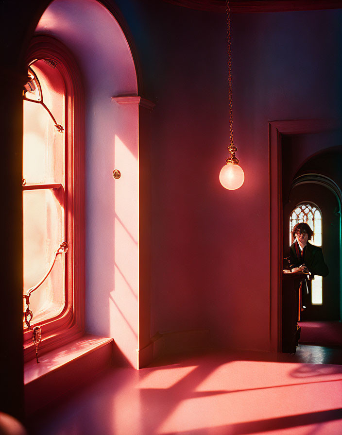 Silhouette of a person in red-lit room with arched windows