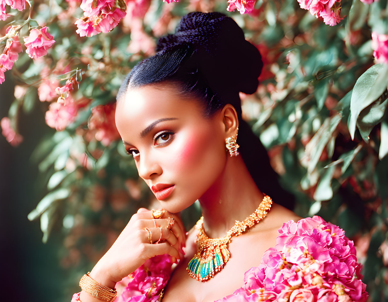Woman with Bun Hairstyle and Gold Jewelry Poses Among Pink Flowers