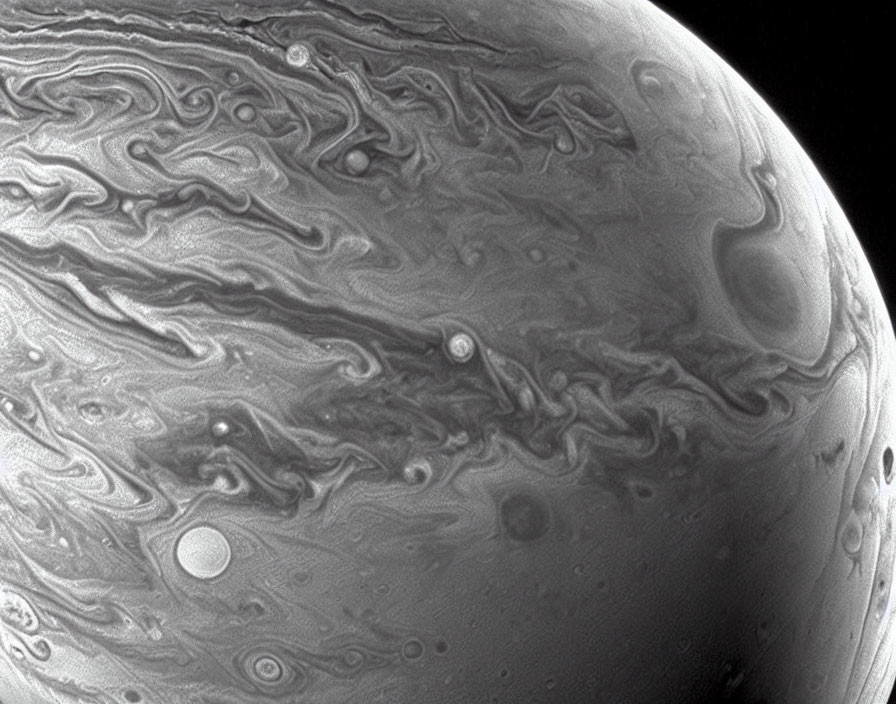 Monochrome close-up view of Jupiter's swirling gas clouds and storm patterns