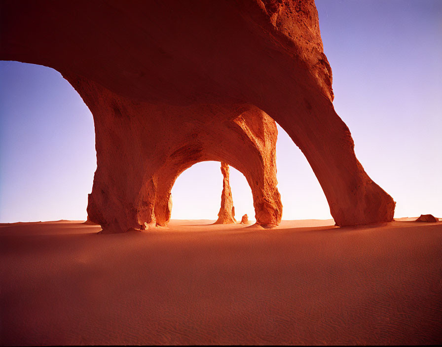 Sandstone Arch Formation in Desert Sands under Clear Blue Sky