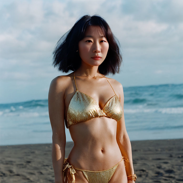 Golden bikini woman on beach with sea and cloudy sky