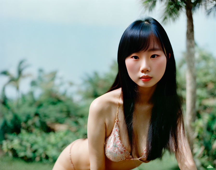 Woman with Long Black Hair in Bikini Against Lush Greenery
