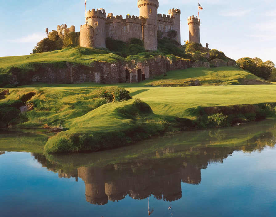 Medieval Castle with Round Towers on Verdant Hill and Tranquil Water Reflections