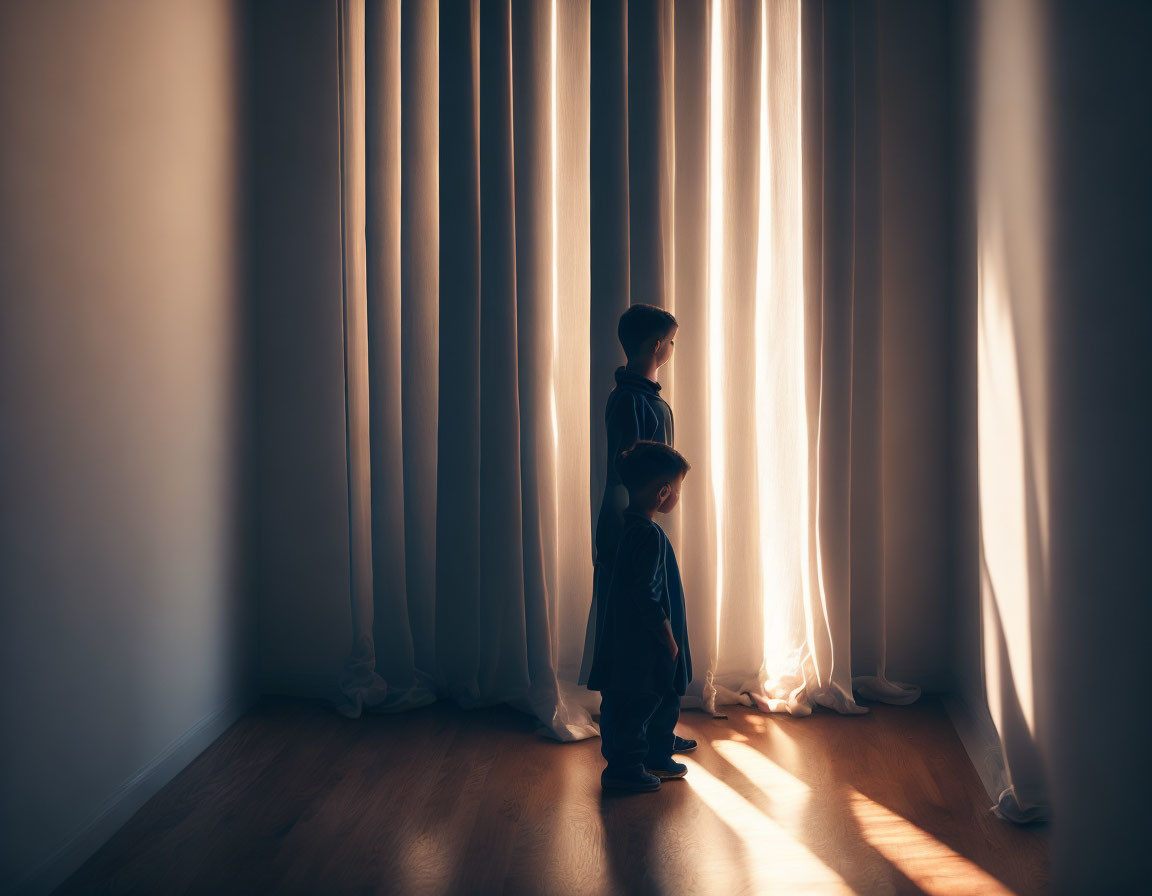 Children standing in dimly lit room with long shadows cast by sunlight.