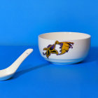 Translucent bowl with spherical objects on blue surface with white spoon