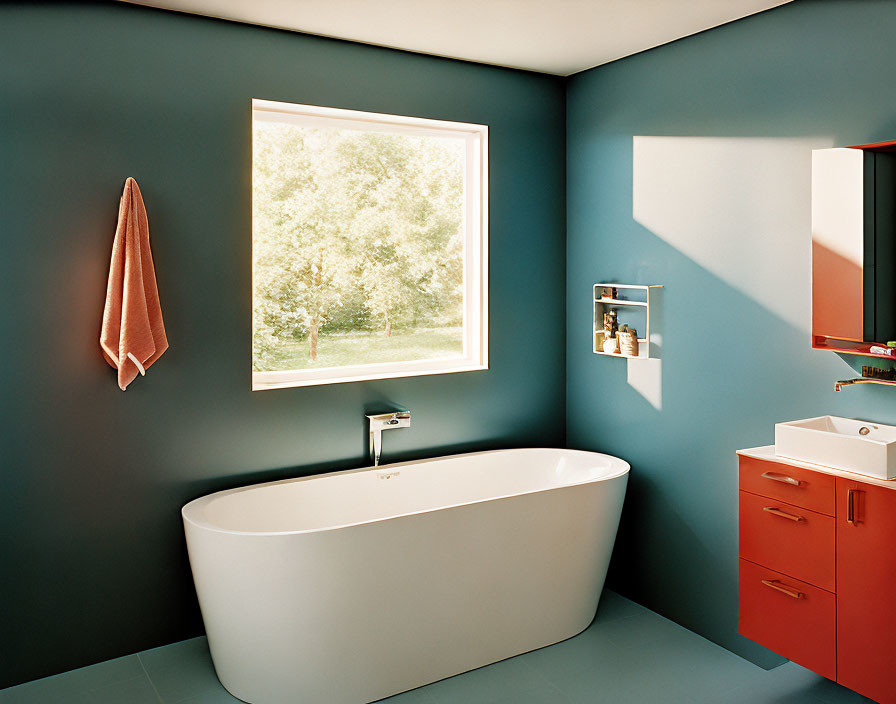 Stylish bathroom with teal walls, freestanding tub, orange cabinet, and large window with