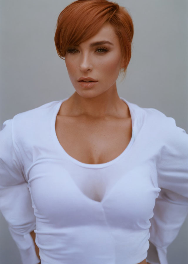 Short Red-Haired Person in White Top on Neutral Background