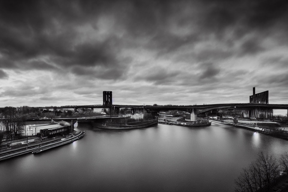 Monochrome cloudy sky over industrial bridges and river.