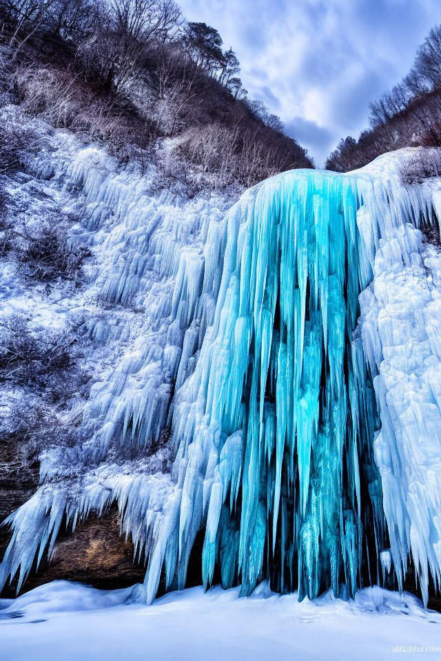 Frozen Waterfall: Vibrant Blue Ice Against Snowy Landscape