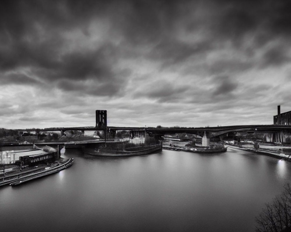 Monochrome cloudy sky over industrial bridges and river.