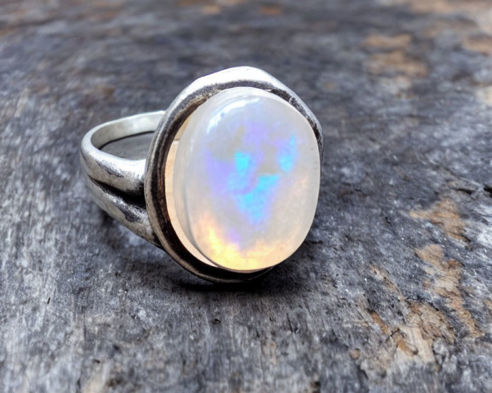 Opalescent gemstone in vintage silver ring on weathered wooden surface