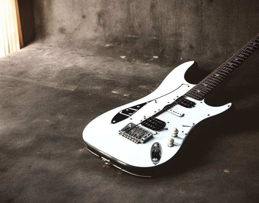 White Electric Guitar with Black Pickguard on Gritty Grey Floor