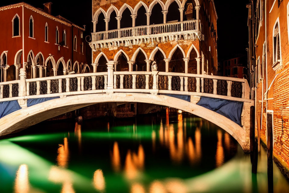 Illuminated Venetian canal with arched bridge at night