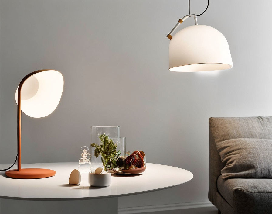 Minimalist Interior Scene with Stylish Lamps, Glass Objects, Plants, and Grey Couch