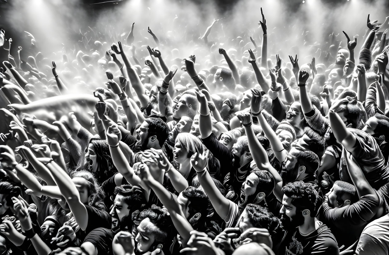 Monochrome image of enthusiastic concert crowd with raised hands