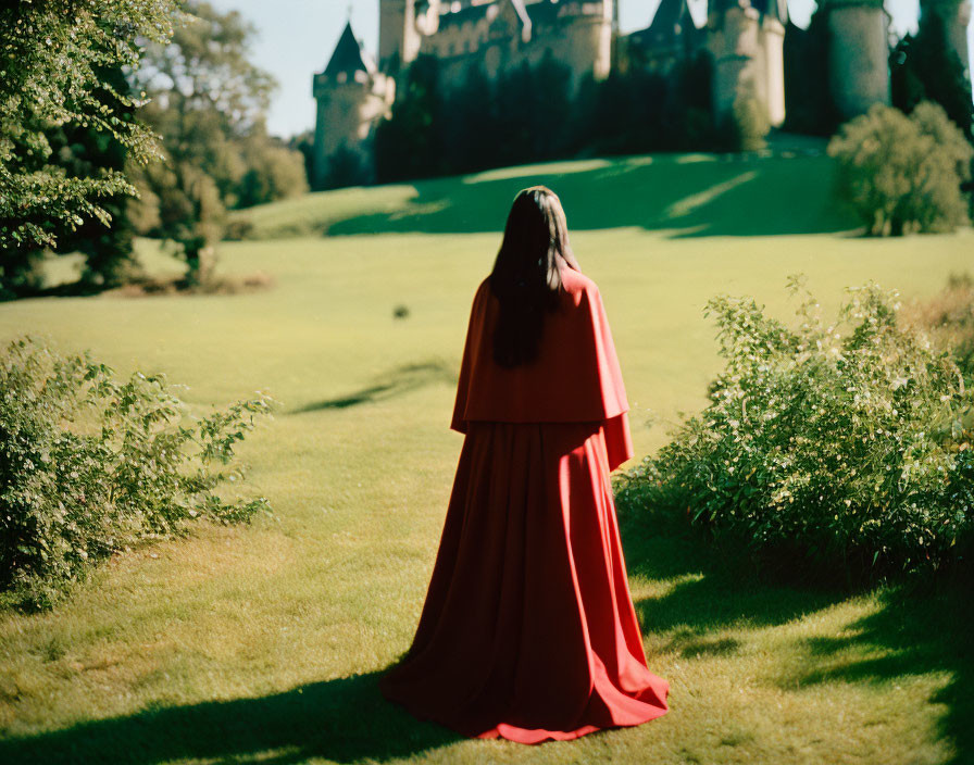 Person in red cloak admiring castle in green field
